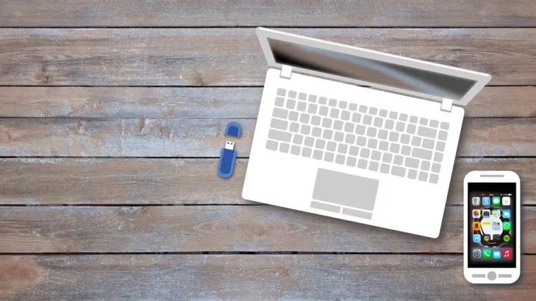 Üstten görülen ahşap masada dizüstü bilgisayar, USB bellek ve akıllı telefon